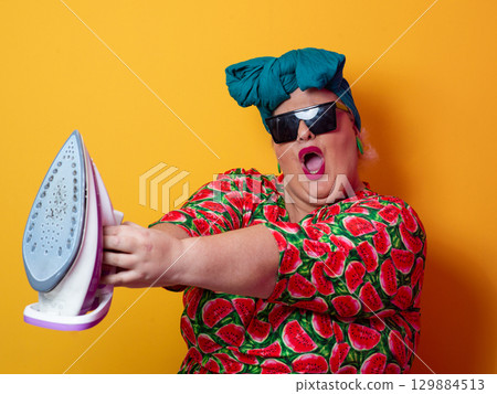 Playful plus size woman aiming iron like weapon in sunglasses 129884513