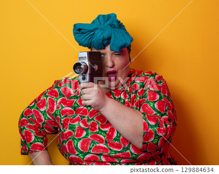 Retro plus size woman filming with vintage camera 129884634