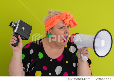 Woman shouting into megaphone and holding vintage camera Woman shouting into megaphone and holding vintage camera 129884667