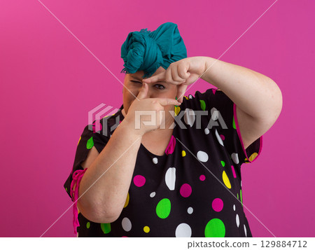 Woman framing face with fingers in creative gesture 129884712