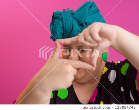 Woman framing face with fingers in creative gesture 129884742