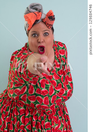 Unimpressed woman in watermelon dress posing with hands on hips 129884746