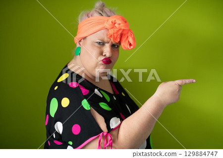 Plus size woman in vibrant polka dot outfit making a comic shrug gesture with outstretched hands and amusing expression. 129884747