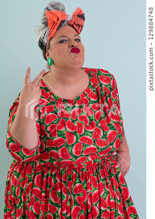 Unimpressed woman in watermelon dress posing with hands on hips Unimpressed woman in watermelon dress posing with hands on hips 129884748