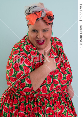 Unimpressed woman in watermelon dress posing with hands on hips Unimpressed woman in watermelon dress posing with hands on hips 129884763