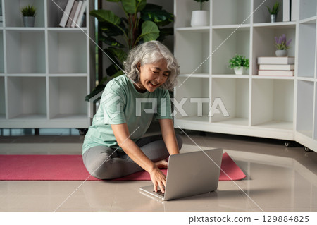 Senior Woman Engaging in Wellness Activities at Home with Laptop for a Healthy Lifestyle and Mental Wellbeing 129884825