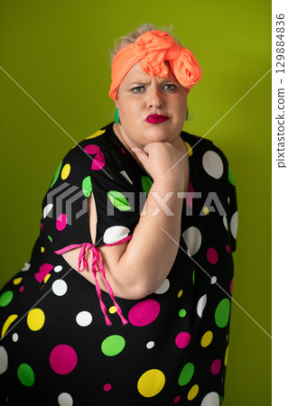 Plus size woman in vibrant polka dot outfit making a comic shrug gesture with outstretched hands and amusing expression. Plus size woman in vibrant polka dot outfit making a comic shrug gesture with outstretched hands and amusing expression. 129884836