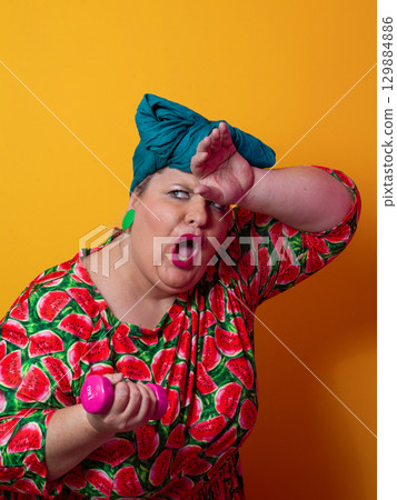 Exhausted plus size woman resting after dumbbell workout 129884886