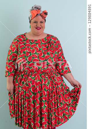 Unimpressed woman in watermelon dress posing with hands on hips 129884891