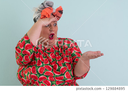 Surprised woman pointing at open hand in studio 129884895