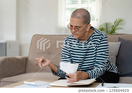 Senior Woman Planning Retirement Finances at Home with Documents and Calculator for Future Security and Comfort Senior Woman Planning Retirement Finances at Home with Documents and Calculator for Future Security and Comfort 129884929