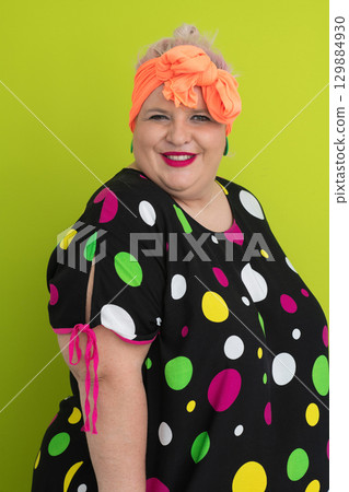 Plus size woman in vibrant polka dot outfit making a comic shrug gesture with outstretched hands and amusing expression. 129884930