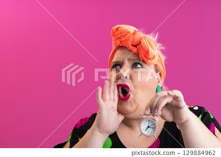 Playful woman in colorful outfit pointing with excited expression 129884962