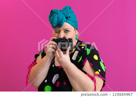 Playful woman aiming camera at viewer in studio 129884967