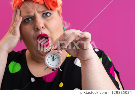Playful woman in colorful outfit pointing with excited expression Playful woman in colorful outfit pointing with excited expression 129885024