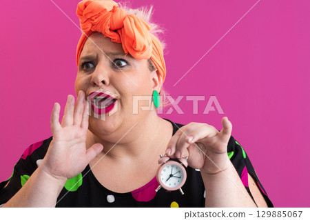 Playful woman in colorful outfit pointing with excited expression 129885067