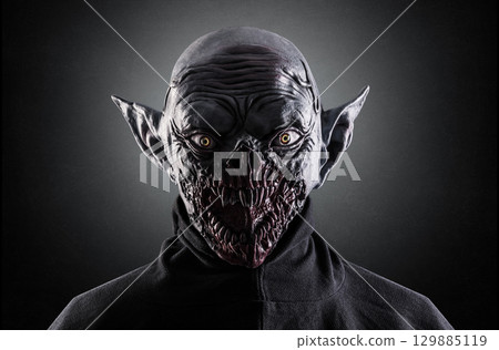 Portrait of a monster with sharp fangs over dark foggy background. 129885119