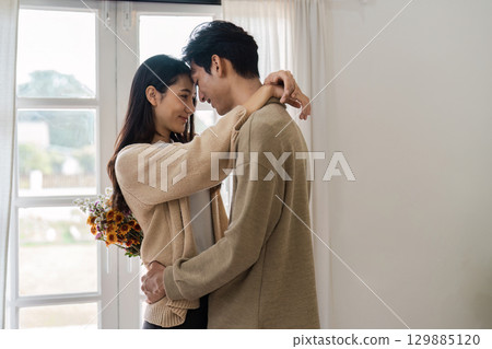 Romantic Couple Embracing in Cozy Home Setting with Natural Light and Warm Atmosphere Romantic Couple Embracing in Cozy Home Setting with Natural Light and Warm Atmosphere 129885120