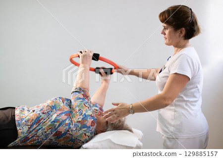 Physiotherapy Session with Elderly Woman Using Exercise Ring Physiotherapy Session with Elderly Woman Using Exercise Ring 129885157