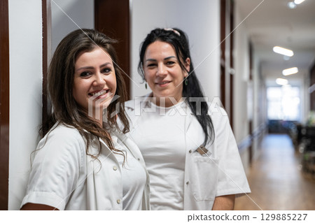 Two nurses take a well deserved break in the hospital hallway, resting after a long and demanding day of patient care. 129885227