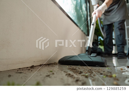 Professional Cleaning Service Worker Vacuuming Outdoor Patio Area with Modern Equipment 129885259