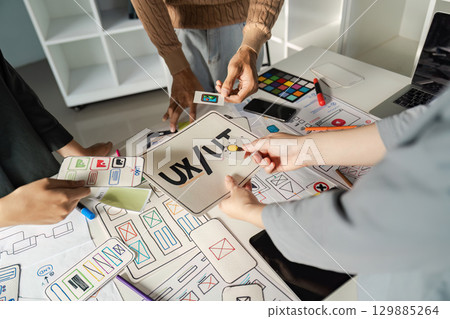 Creative UX UI Design Brainstorming Session with Designers Collaborating on Innovative Ideas and Wireframes 129885264