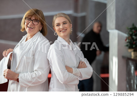 Healthcare workers smiling back to back in clinic Healthcare workers smiling back to back in clinic 129885294