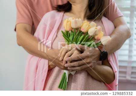 Senior Couple Celebrating Valentine's Day with Love and Joyful Embrace Holding Flowers Senior Couple Celebrating Valentine's Day with Love and Joyful Embrace Holding Flowers 129885332