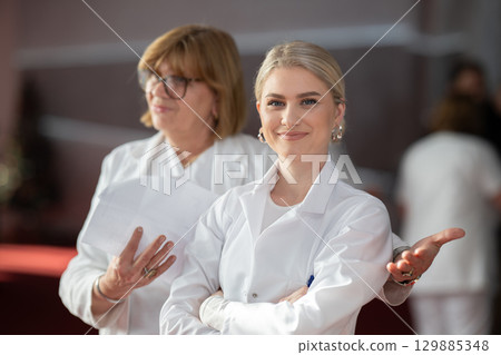 Young female doctor posing in front of medical staff Young female doctor posing in front of medical staff 129885348