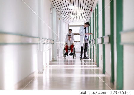 Young Male Patient in Wheelchair Assisted by Female Medical Professional 129885364