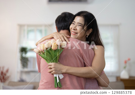 Happy Senior Couple Celebrating Valentine's Day with Love and Joyful Embrace in Cozy Home Setting 129885378
