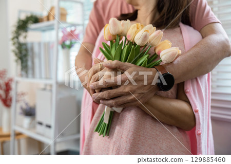 Senior Couple Celebrating Valentine's Day with Flowers and Love in a Cozy Home Setting 129885460