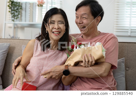 Joyful Couple Celebrating Valentine's Day with Flowers and Gifts in a Cozy Home Setting 129885540