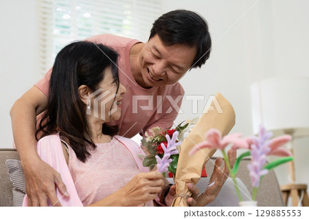 Romantic Couple Sharing a Joyful Moment with Flowers on Valentine's Day in a Cozy Home Setting Romantic Couple Sharing a Joyful Moment with Flowers on Valentine's Day in a Cozy Home Setting 129885553
