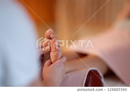 Foot Massage Therapy in a Relaxing Spa Setting. A professional massage therapist in a white uniform provides a soothing foot massage to a client in a calm and serene spa environment Foot Massage Therapy in a Relaxing Spa Setting. A professional massage therapist in a white uniform provides a soothing foot massage to a client in a calm and serene spa environment 129885560