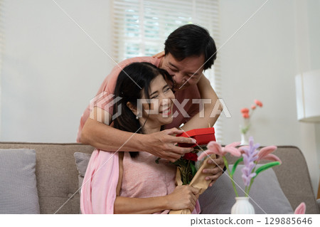 Senior Couple Celebrating Valentine's Day with Gifts and Flowers in a Cozy Home Setting 129885646