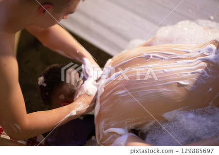 Back Massage with Foam.Therapist applying soap foam with hands on patient back during traditional bath ritual. 129885697