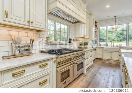 A large kitchen with a white stove and oven, and a window above it 129886011