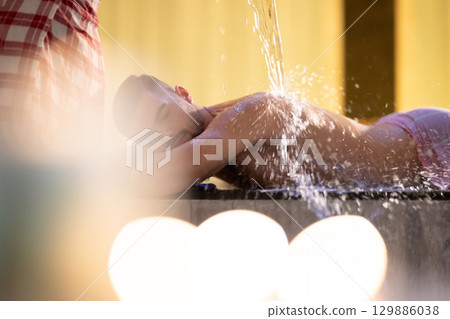 Man receiving water therapy inside a traditional Turkish hammam with ornate details. Man receiving water therapy inside a traditional Turkish hammam with ornate details. 129886038