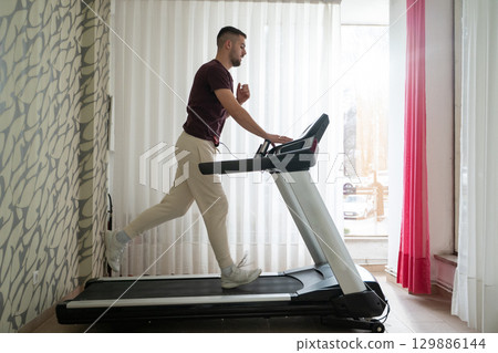 Running Therapy Indoors on Treadmill.Man running indoors on treadmill as part of a physical recovery program. 129886144