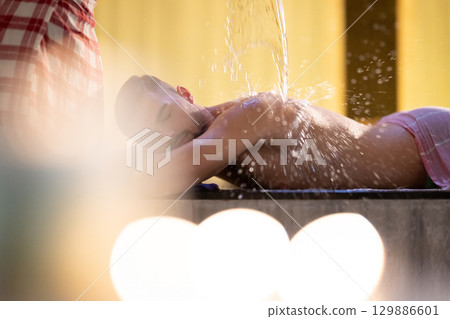 Man receiving water therapy inside a traditional Turkish hammam with ornate details. Man receiving water therapy inside a traditional Turkish hammam with ornate details. 129886601