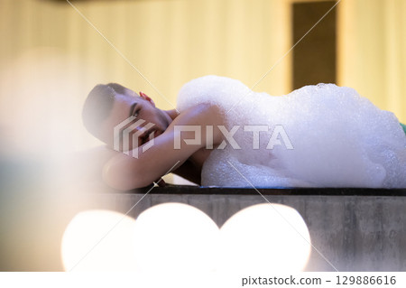 Man Relaxing in Foam.Relaxed man lying in Turkish bath covered in white foam during cleansing ritual. 129886616
