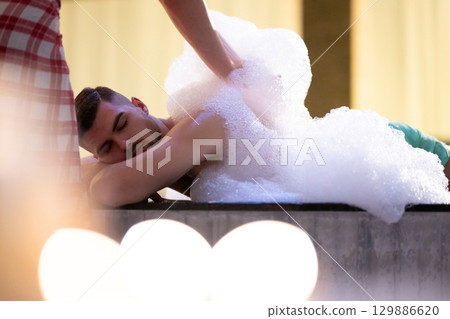 Foam Massage Session.Hamam attendant applying foam massage on patient back with circular motions. 129886620
