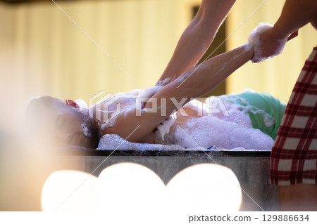 Hand Foam Therapy. Attendant gently washing patient hands with foamy soap in traditional bath setting. Hand Foam Therapy. Attendant gently washing patient hands with foamy soap in traditional bath setting. 129886634