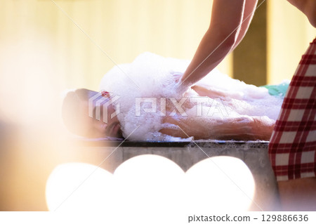 Back Massage with Foam.Therapist applying soap foam with hands on patient back during traditional bath ritual. 129886636