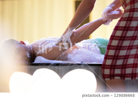 Hand Foam Therapy. Attendant gently washing patient hands with foamy soap in traditional bath setting. Hand Foam Therapy. Attendant gently washing patient hands with foamy soap in traditional bath setting. 129886668