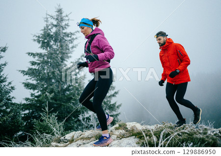 Trail running couple man and woman running on a mountain path Trail running couple man and woman running on a mountain path 129886950