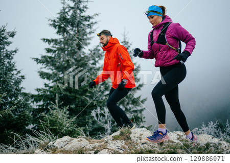 Trail running couple man and woman running on a mountain path 129886971