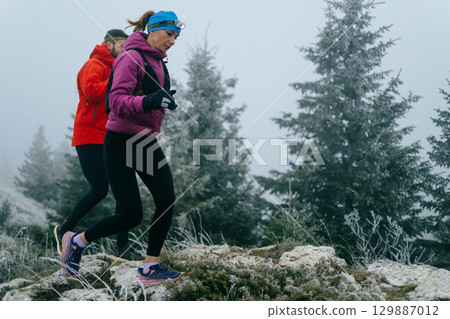 Trail running couple man and woman running on a mountain path 129887012