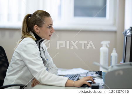 Female doctor working on computer in clinic 129887026